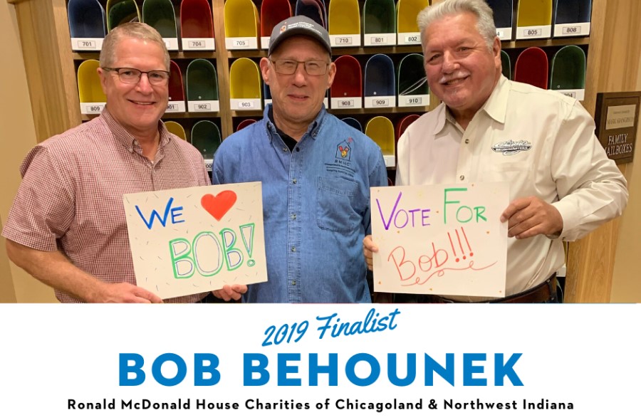 Three men stand together, two of the men hold signs that read "Vote for Bob!"