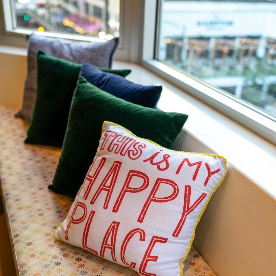 Pillow on a window seat that reads "This is my happy place."