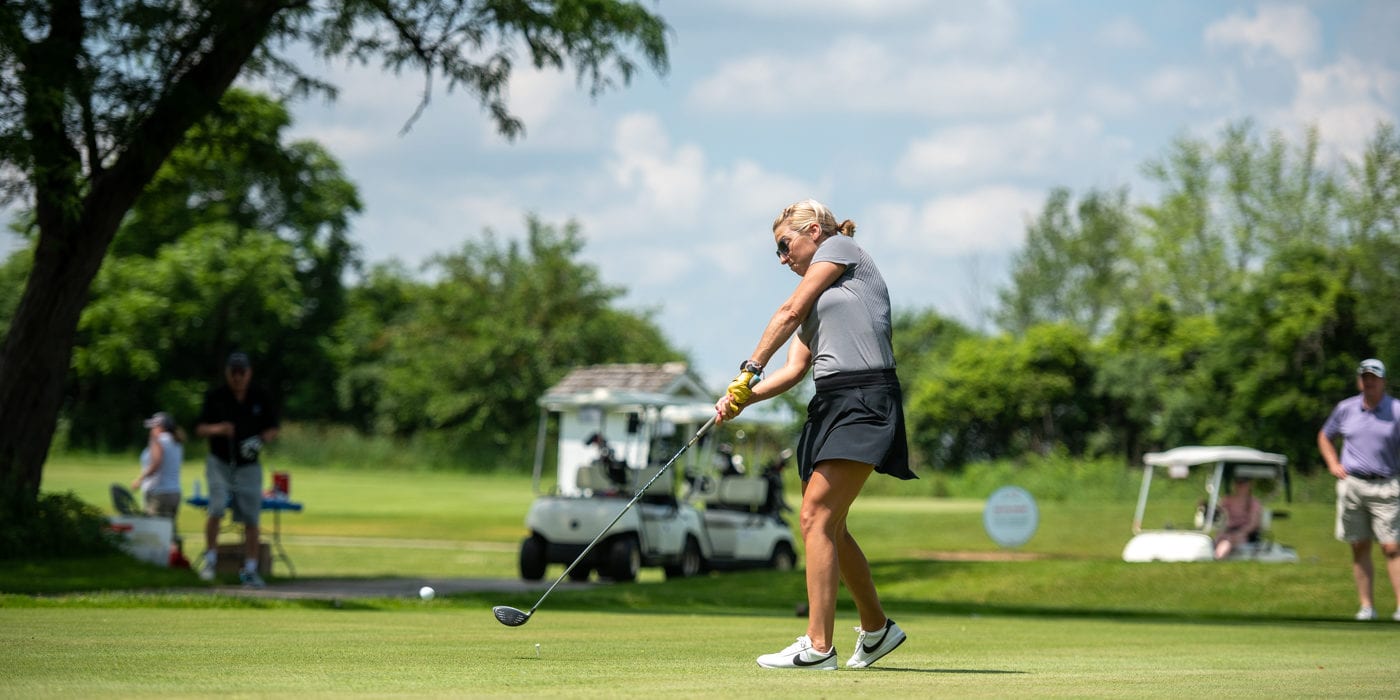White woman swings a golf club