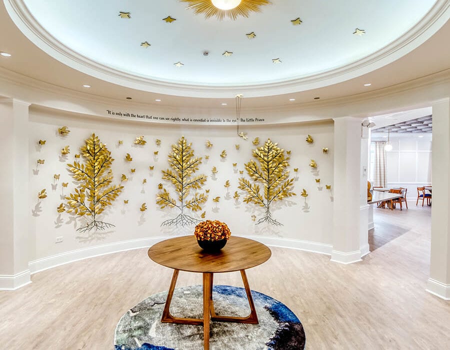 Entryway with a table and the back wall filled with gold tree embellishments.