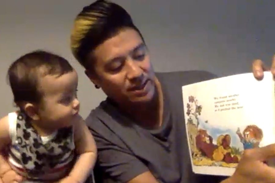 A young man reads a book to a baby.