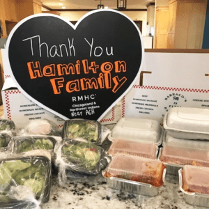 Containers of meals sit in front of a heart-shaped sign that reads "Thank you Hamilton family"
