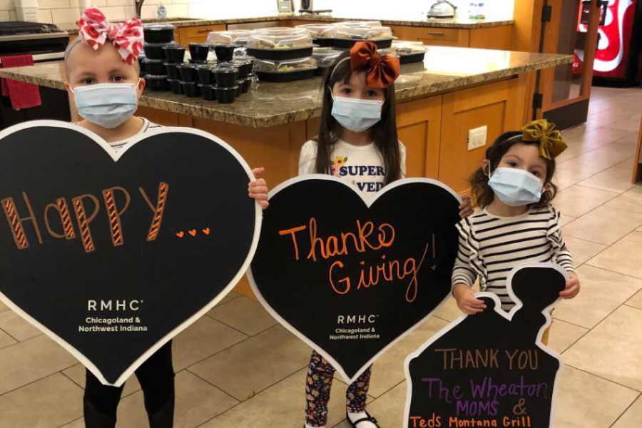 Three young girls hold heart signs that read "Happy Thanksgiving"