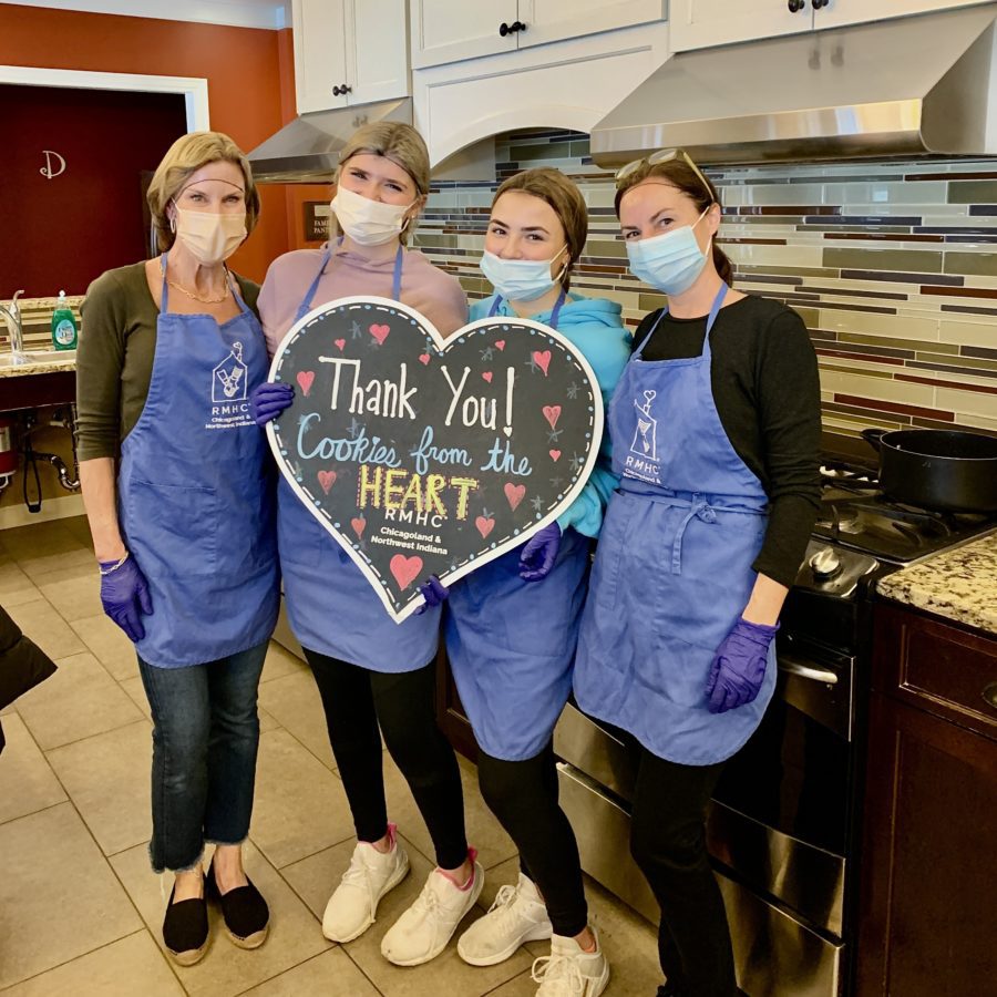 Four women in a kitchen hold a sign that reads "Thank you Cookies from the Heart!"